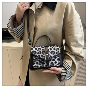 Detail of small leopard print handbag with V-shaped flap and gold metal buckle