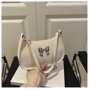Détail d'un sac baguette en cuir blanc crème avec un ornement papillon en métal argenté