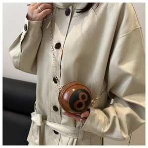 Detailed view of the 8 ball round mini bag with gold chain strap on a trench coat