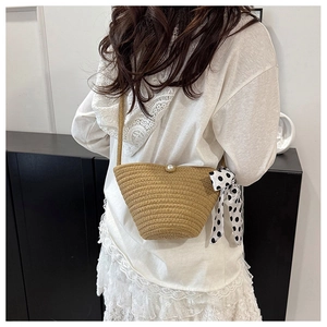 Détail d'un sac bandoulière en paille tissé avec perle blanche et foulard à pois élégant