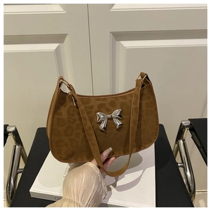 Détail de la boucle papillon argentée sur un sac sous le bras léopard avec fermeture éclair