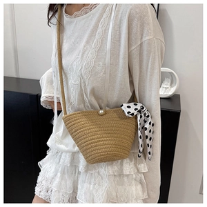Vue détaillée d'un sac seau tressé beige avec perle et foulard à pois porté par un mannequin