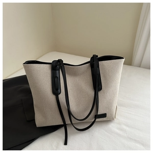 Dettaglio della borsa tote in tela color crema con finiture in pelle nera e logo
