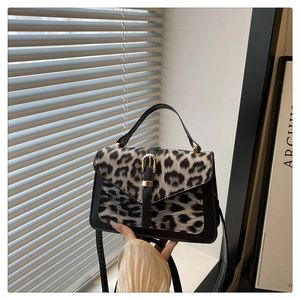 Close-up of leopard print shoulder bag with gold buckle and matte black leather trim