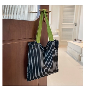 Détail d'un sac cabas en toile avec anses vertes et rayures verticales noires