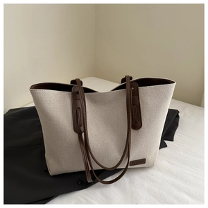 Dettaglio della borsa tote in tela con trama beige e manico in pelle marrone scuro