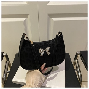Détail d'un sac à bandoulière en velours noir imprimé léopard avec boucle papillon argent