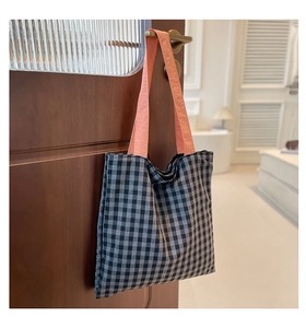 Détail du sac cabas en toile à carreaux avec des poignées orange contrastantes chic