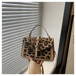 Detail of trendy leopard print handbag with contrast faux pony hair and gold buckle