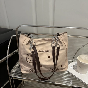 Beige nylon tote bag with cat prints and metal chain straps on a silver shelf