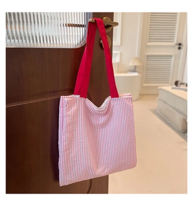 Vue détaillée du sac cabas en toile rayé rose avec poignées rouges sur une poignée