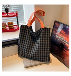 Détail du sac cabas en toile à carreaux noir et blanc avec bandoulière orange vif