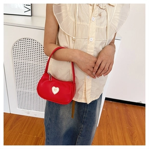 Close-up of a red mini handbag featuring a white heart patch with a bow pattern