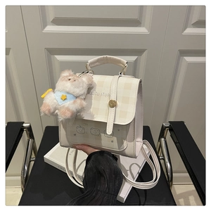 Detail of cream plaid mini backpack with cartoon bear print and plush bear charm accessory
