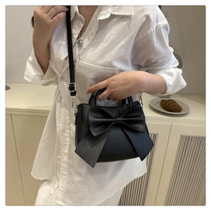 Detail of black crossbody bag with large bow and adjustable shoulder strap for women