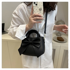 Detailed view of black matte leather shoulder bag with a large bow and gold hardware