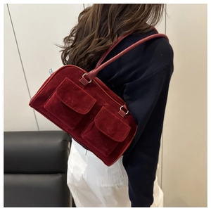 Détail du sac à bandoulière en daim rouge avec poches à rabat porté par un mannequin