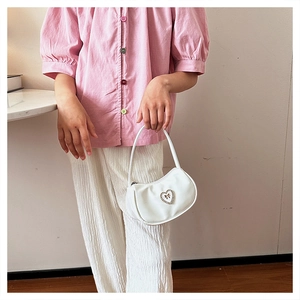 Detail einer weißen Halbmond-Tasche mit glitzernder Herz-Strass-Schleife für Damen