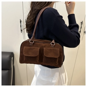 Detail of vintage brown suede shoulder bag featuring dual front pockets and leather straps