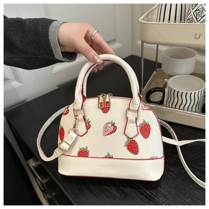 Detail of strawberry print shell bag with red piping and gold-toned metal zipper