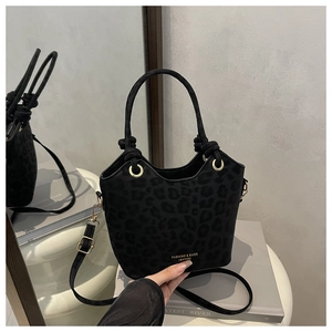 Detail of black leopard print bucket bag with gold hardware and sleek round handle