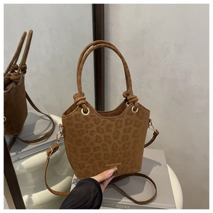 Detail of a dark brown leopard print bucket bag with suede texture and gold eyelets