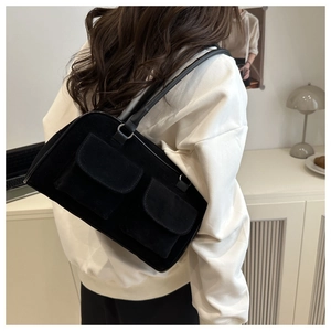 Détail d'un sac cabas noir mat avec doubles poches à rabat porté par un modèle