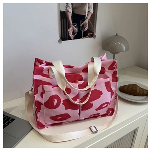 Borsa tote con stampa mucca rosa e rossa e tracolla su una scrivania minimalista