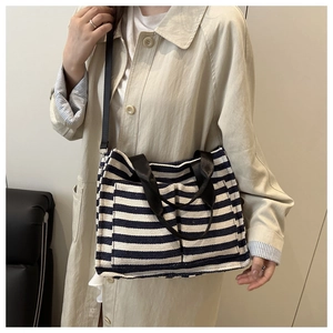 Detail of navy blue striped canvas tote bag featuring two front pockets and woven straps