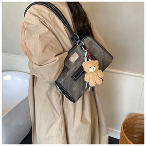 Détail du sac cabas gris vintage avec breloque ours porté par un mannequin pour la taille