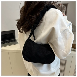 Détail de la bandoulière plissée et du ruban sur un sac sous le bras en daim noir