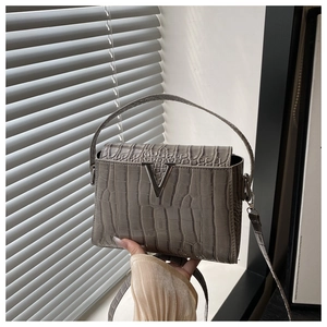 Detail of grey crocodile embossed handbag with silver metal V-shaped buckle and strap