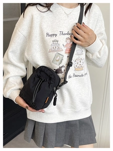 Detail view of black nylon crossbody bag featuring embossed logo and adjustable strap