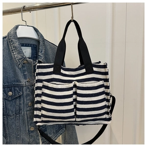 Detail of striped canvas tote bag with dual front pockets and adjustable black strap