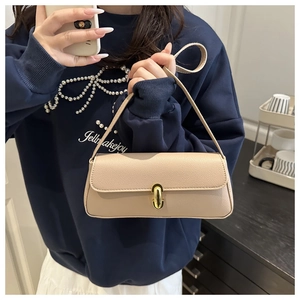 Detail of beige faux leather baguette bag featuring a gold oval twist lock closure