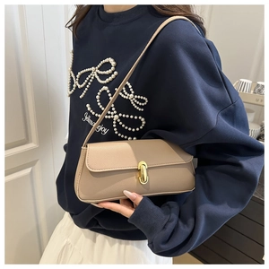 Macro detail of the beige lychee pattern leather shoulder bag with minimalist gold clasp