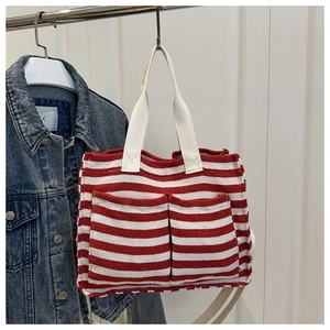 Detail view of red and white striped canvas tote bag with front pockets and sturdy handles