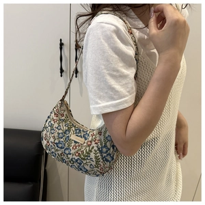Detail of floral tapestry moon bag showing intricate jacquard fabric and gold zipper
