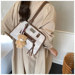 Détail du sac cabas en toile avec garniture en similicuir brun et breloque ours en peluche
