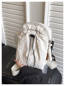 Détail du sac à cordon en nylon beige avec broderie blanche et étiquette orange