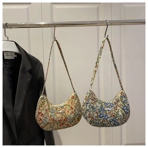 Detailed view of floral jacquard linen underarm bags with metallic brand plaque
