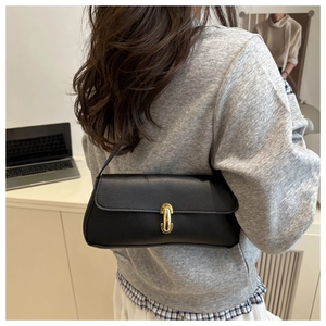 Close-up of black pebble leather shoulder bag with gold saddle buckle detail