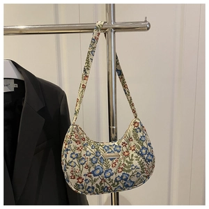 Close-up of floral linen hobo bag with a metal plaque detail on a black blazer background