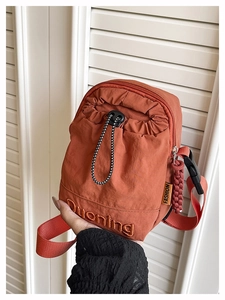 Detail of red nylon crossbody bag showing the drawstring pocket and logo embroidery