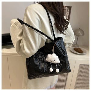 Lifestyle view of black quilted tote bag with bear pattern and cloud charm on shoulder