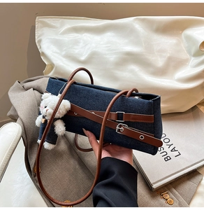 Detail of dark blue denim handbag with brown leather straps and cute plush bear charm