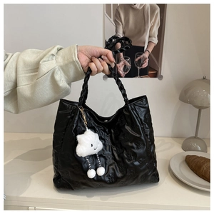 Detail of black tote bag with embossed bear patterns and a white cloud plush charm