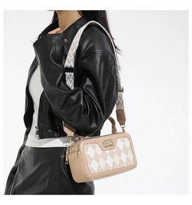 Detail of crossbody bag with beige and brown checkered pattern and woven strap