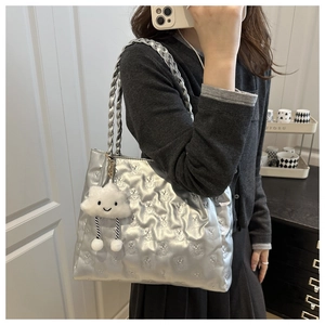 Close-up of silver tote bag with embossed bear pattern and soft cloud charm accessory