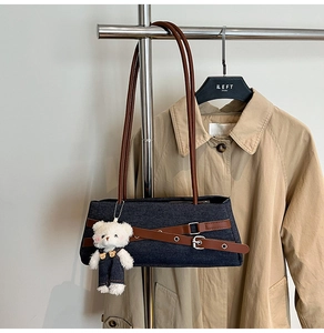 Close-up of denim shoulder bag with brown leather straps and cute bear charm